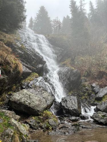 a waterfall on the side of a mountain with rocks at Koralpen Appartement in Rieding