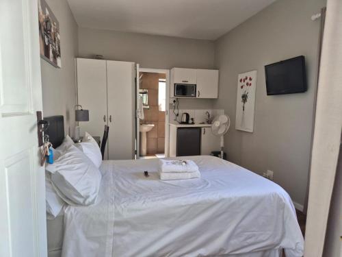 a bedroom with a white bed and a kitchen at Afton Safari Lodge in Cape Town