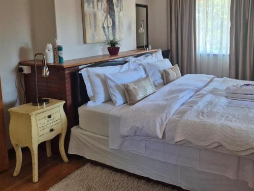 a bedroom with a large bed and a night stand at Afton Safari Lodge in Cape Town