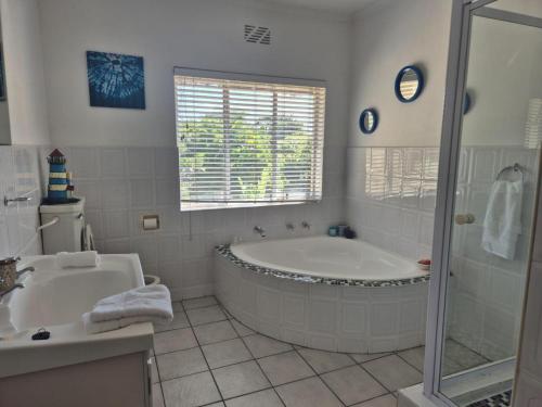 ein weißes Badezimmer mit Badewanne und Waschbecken in der Unterkunft Afton Safari Lodge in Kapstadt