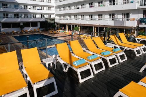 a group of yellow lounge chairs next to a swimming pool at Port Fiesta Park in Benidorm