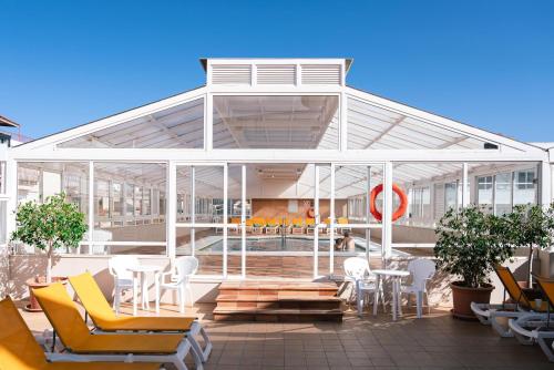 a building with a conservatory with chairs and a pool at Port Fiesta Park in Benidorm