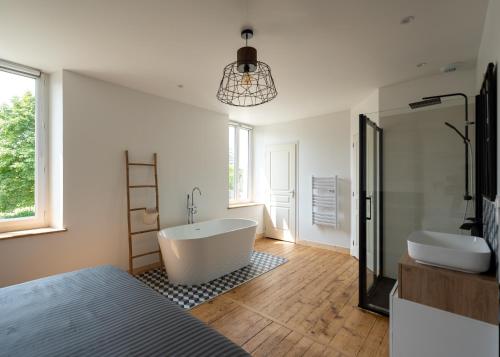 a bathroom with a tub and a sink and a bed at Gîte du Manoir de Berville in Saint-Pierre-sur-Dives