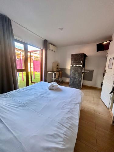 a bedroom with a large white bed and a window at Hôtel Acajou in Argelès-sur-Mer