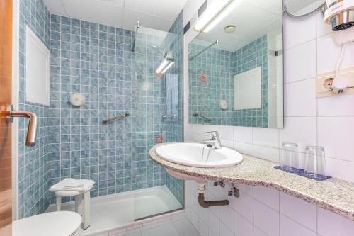 a blue tiled bathroom with a sink and a toilet at Port Fiesta Park in Benidorm