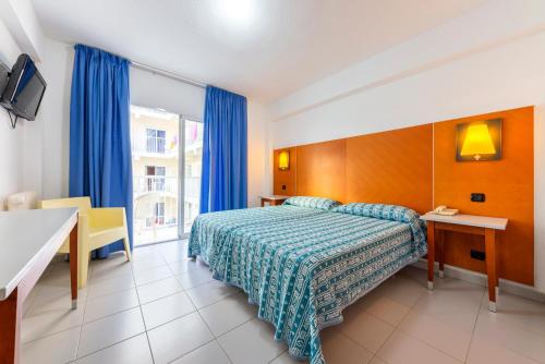 a hotel room with a bed and a desk and a window at Port Fiesta Park in Benidorm