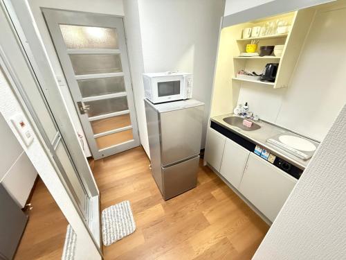 a small kitchen with a refrigerator and a microwave at Discover Fukuoka House in Fukuoka