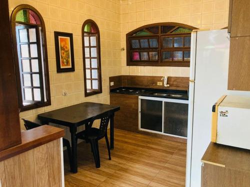 a kitchen with a black table and a refrigerator at LINDA CASA A 500mts da PRAIA DE CIBRATEL PARA CURTIR COM AMIGOS E FAMILIA in Itanhaém