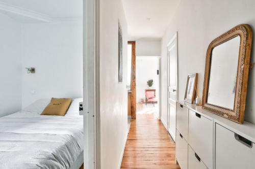 une chambre blanche avec un lit et un miroir dans l'établissement Spacieux appart vue Montmartre, à Paris