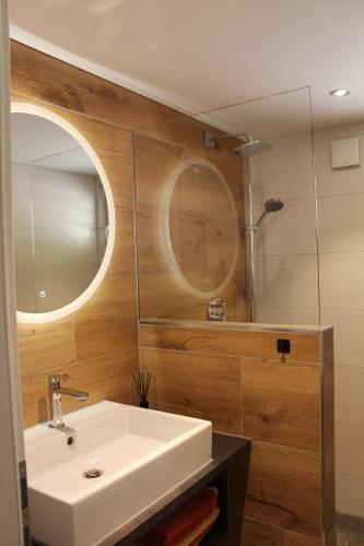 Un baño con un lavabo blanco y un espejo. en Separates Ferienhaus Speicherhäusle auf dem Hasenhof mit eigener Terrasse mit Grill, Kachelofen, WLAN, en Hornberg