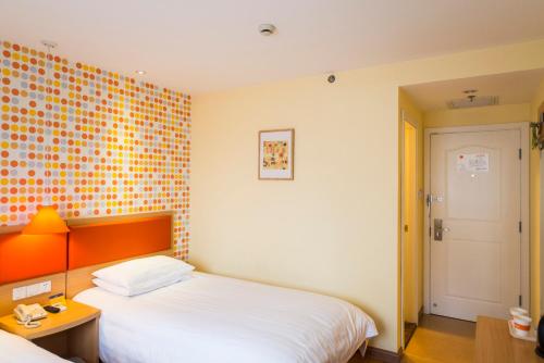 a bedroom with a white bed and an orange wall at Home Inn Shijiazhuang West 2nd Ring Road Huai'an Road in Shijiazhuang