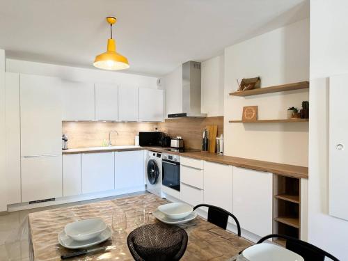 Una cocina con gabinetes blancos y una mesa con sillas. en Nouveauté ! Bel'Orizonte T - Deux Chambres proche mer, en Propriano