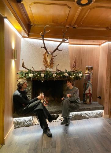 two men sitting in front of a fireplace at Hotel Isolabella Wellness in Fiera di Primiero