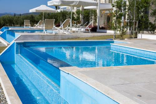a blue swimming pool with chairs and an umbrella at Nikiti Dream Villas in Nikiti