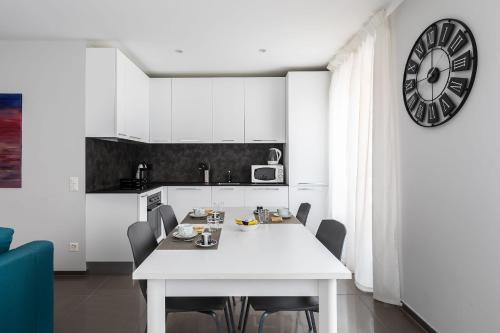 a kitchen with a white table and a clock on the wall at Maraini 35 by Quokka 360 - strategic location near Lugano station in Lugano