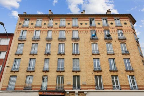 un grand bâtiment en briques avec de nombreuses fenêtres dans l'établissement Comfort and modernity at Saint-ouen, à Saint-Ouen