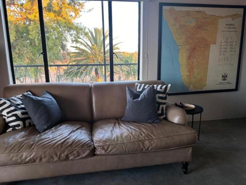 a brown couch in a room with a large window at Otjiwarongo Farmstay in Otjiwarongo