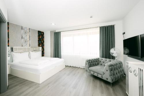 a white bedroom with a bed and a chair at PARKHOTEL BRAUNAU - 24 Stunden Self Check-IN in Braunau am Inn