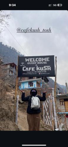 a person with a backpack standing in front of a sign at Cafekush tosh in Tosh