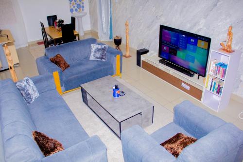 a living room with blue couches and a tv at APPARTEMENT BAM in Cotonou