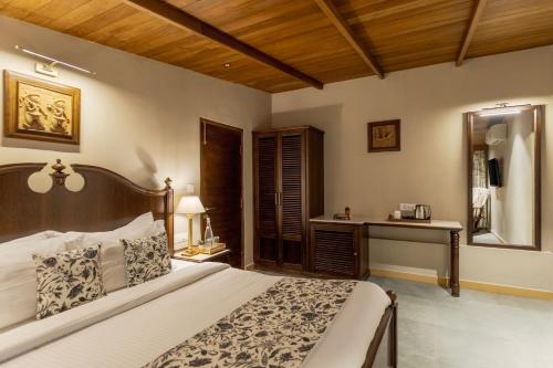 a bedroom with a large bed and a desk at SaffronStays Sylvan Farms in Delmāra
