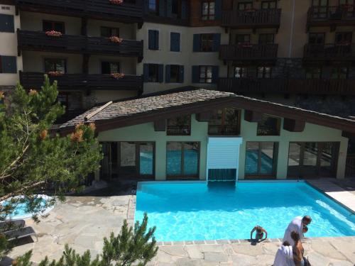 une piscine devant un immeuble dans l'établissement ARCS 1950 Prince des Cimes 2 chambres 6 pers orienté sud ouest Piscine Jacuzzi Sauna Hammam, à Arc 1950