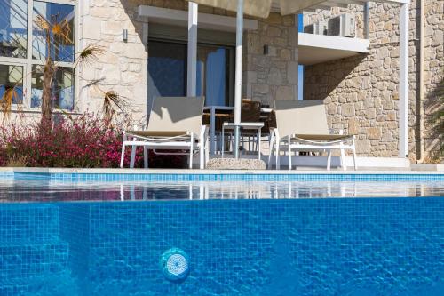 a swimming pool with chairs next to a house at Nikiti Dream Villas in Nikiti