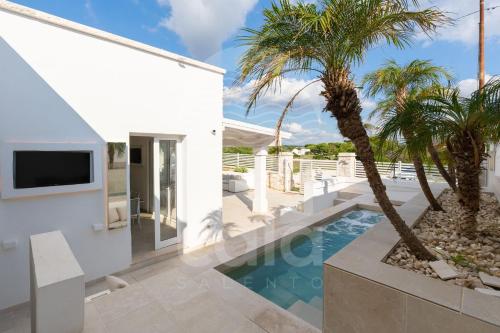 een wit huis met een zwembad en palmbomen bij Villa Chicadee - piscina privata - by Cala Salento in Campomarino