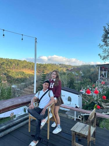 a man and a woman sitting on a chair on a deck at Lưng Chừng House in Da Lat