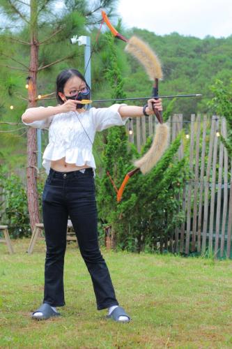 a woman holding a bow and arrows in a field at Lưng Chừng House in Da Lat