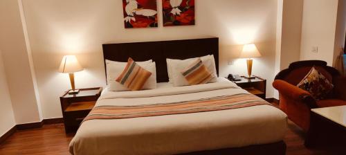 a bedroom with a bed with two lamps and a chair at GOODWILL HOTEL in New Delhi