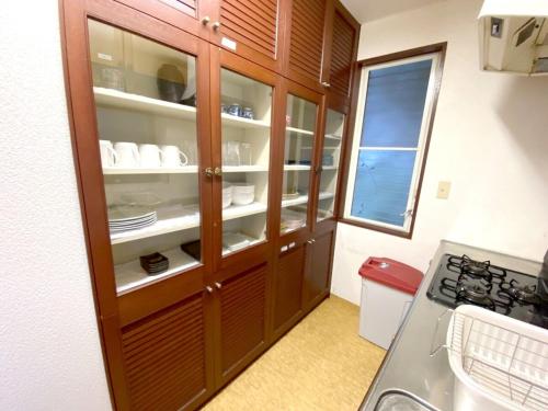 una cocina con armarios de madera con platos y platos en 絶景温泉付き別荘, en Higashiizu