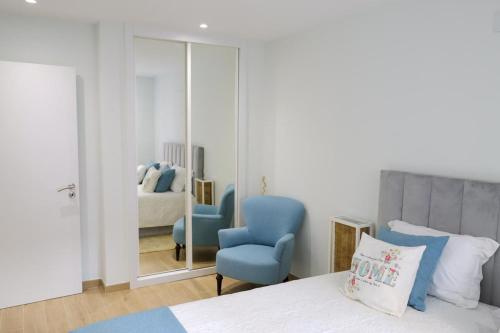 a bedroom with a blue chair and a mirror at Dunas Ria Apartment T2 in Gafanha da Encarnação