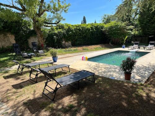 une piscine avec deux bancs et une table à côté dans l'établissement Grand Maison avec Piscine et Sauna, à La Ferté-Gaucher