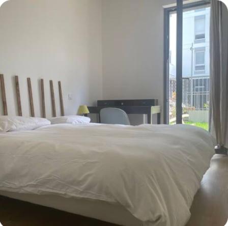 une chambre avec un grand lit avec un bureau et une fenêtre dans l'établissement Le Familial - À deux pas de Paris - 03B, à Rueil-Malmaison