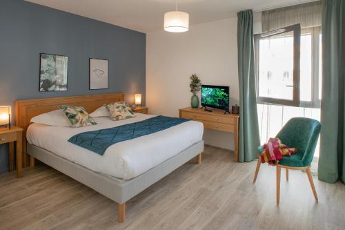 a bedroom with a bed and a chair and a television at Domitys Calandra in Villepinte
