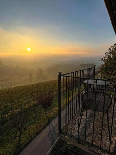 a table and chair on a balcony with the sunset at Relais Castello di Razzano in Alfiano Natta
