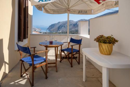 a balcony with a table and chairs and an umbrella at Villa Elizabeth in Symi