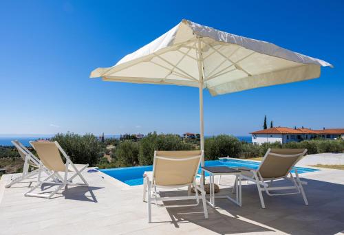 a patio with a table and chairs and an umbrella at Nikiti Dream Villas in Nikiti