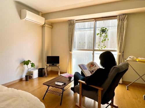 a woman sitting in a chair reading a book in a room at 美咲旅館 in Sakaide
