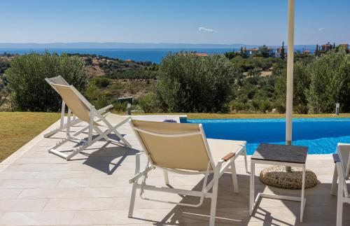 a group of chairs and a table next to a pool at Nikiti Dream Villas in Nikiti