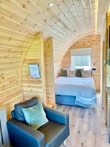 a bedroom with a bed and a couch in a room at Luxury Glamping Pod - Garthside Farm Holidays in Brampton