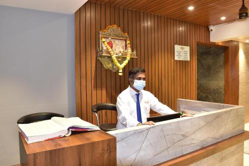 a man in a mask sitting at a desk at Hotel Candor Amigo Airoli Mind Space in Navi Mumbai