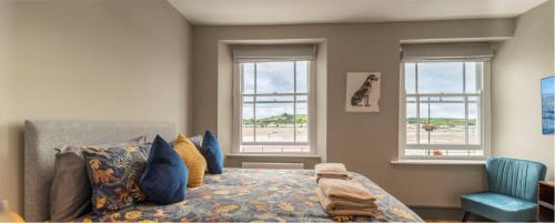 a bedroom with a bed and windows with a beach at Sailors Rest in Appledore