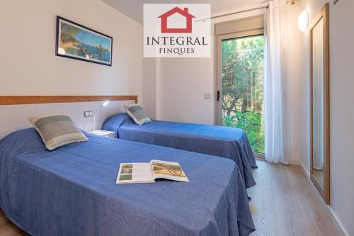zwei Betten in einem Hotelzimmer mit einem Buch darauf in der Unterkunft El Coralí Apartament Palamós in Palamós