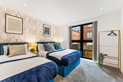two beds in a room with a window at Contemporary Leeds Apartment - Free Parking in Leeds