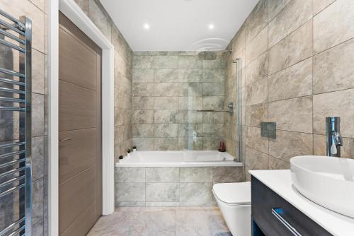 a bathroom with a tub and a toilet and a sink at Contemporary Leeds Apartment - Free Parking in Leeds