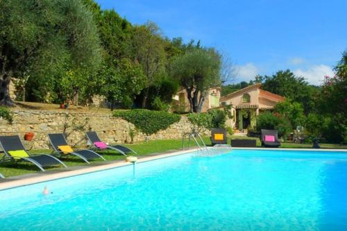 une grande piscine avec des chaises et une maison dans l'établissement Villa La Mauvaise Herbe - Welkeys, à Mougins