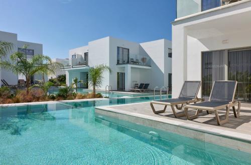a swimming pool with two chairs next to a building at Atlantica Sungarden Park in Ayia Napa