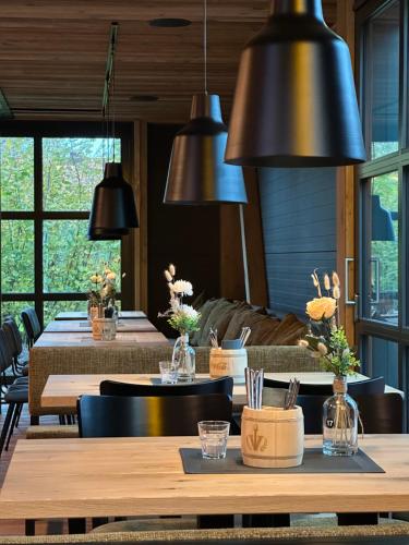 a dining room with tables and black pendant lights at Vareler Brauhaus-Hotel Varel Dangast in Varel